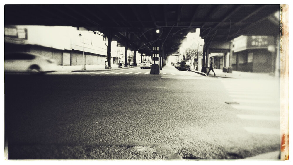 an edited photo titled 'Fordham Flux', from the City Slick collection of JTJ' White's City Series photography. The image is a black and white photograph of the corner of Jerome Avenue and Fordham Road in The Bronx.